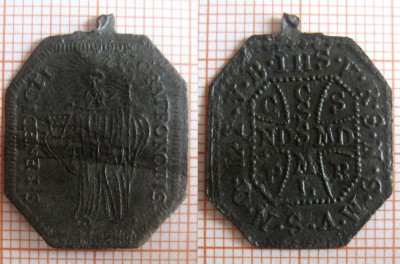 3. Av: stojící postava s biskupskou holí v levé ruce, v pravé ruce drží pohár, kolem hlavy svatozář, okraj lemovaný perlovcem, po pravé a levé straně postavy opis: S.BENEDICTI.ORAPRONOBIS. Rv: v perlovci okolo vnějšího obvodu opis IHS.V.R.S.N.S.M.V.S.M.Q.L.I.V.B. od opisu perlovcem oddělený a  uprostřed umístněný kříž   sv.Benedikta, uvnitř opis, svislé břevno: CSSML, vodorovné břevno NDSMD, mezi rameny: C S P B. 25x19,6x0,5mm 0,76g. Měď - ražba.